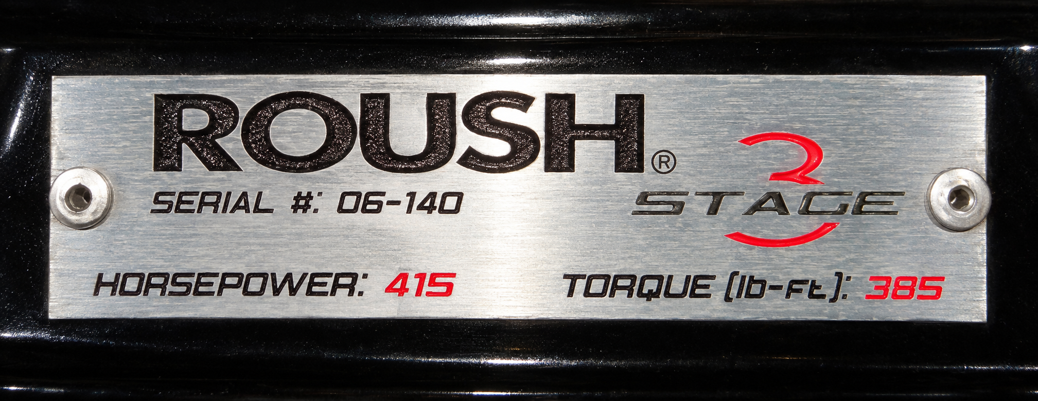 Brushed-metal ROUSH plaque printed with a serial number of 06-140, the model name Stage 3, horsepower of 415 and torque of 385 pound-feet, fastened with two bolts.